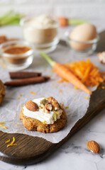 Keto Carrot oatmeal cookies. Healthy homemade ketogenic diet dessert decorated with white cream, nut and seeds. set on white cafe table background.