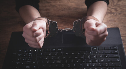 Hands in handcuffs on laptop keyboard. Cyber Crime
