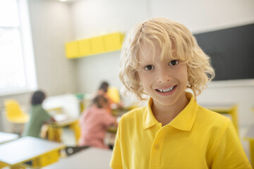 Cute schoolboy in yellow tshirt smiling nicely