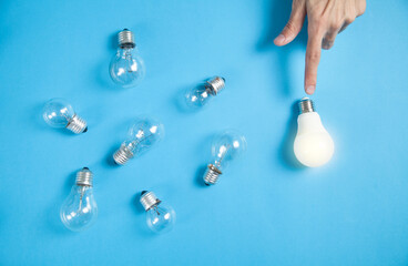 Male hand pointing light bulb in the blue background.