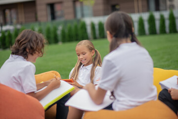 Children in white shirts sitting and studying together outside