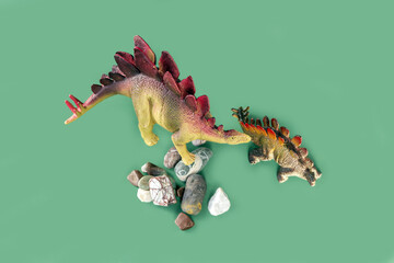 Stegosaurus dinosaurs toy on stones on green background. Mom and cub