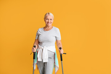 Mature woman with walking poles on color background