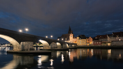 Fototapeta na wymiar Steinerne Brücke in Regensburg mit Dom und Donau bei Nacht mit Wolken