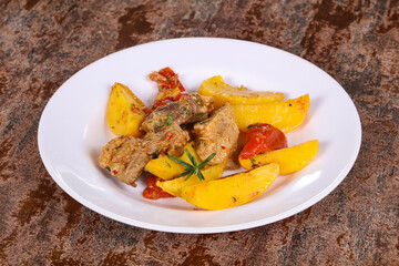 Baked pork meat with potao and tomato