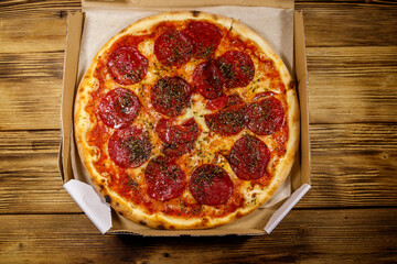 Delicious fresh pizza in cardboard box on a wooden table. Top view. Concept for home delivery of food, fast food, delivery of pizza