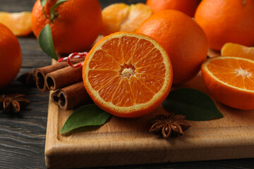 Board with mandarins and cinnamon on wooden background