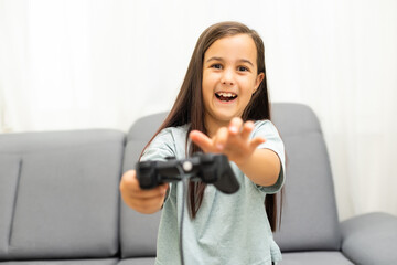 Fototapeta na wymiar Girl with joystick. Excited little girl playing video game and smiling