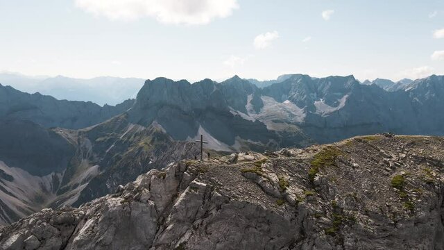 Aerial jib down shot of two people beside Sonnjoch mountain summit cross in Austria