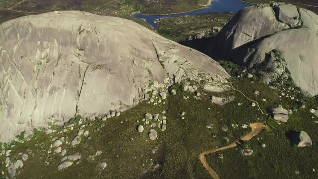 Aerial - Tilt-up shot of granite monolith of Paarl Mountain, Nantes dam in background