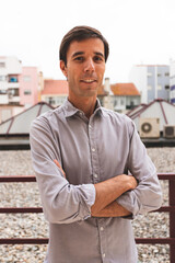 Vertical portrait of a young business man working as architect in Lisbon. Portrait of a young guy with the city in the background, wearing an elegant shirt after work