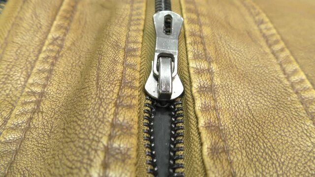 The zipper opens on the brown leather jacket.