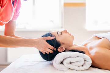 Close-up of a beautiful brunette woman receiving a head massage in a Spa center