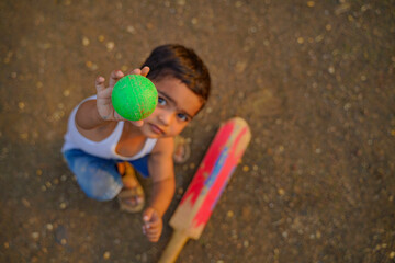 small indian child playing cricket at home