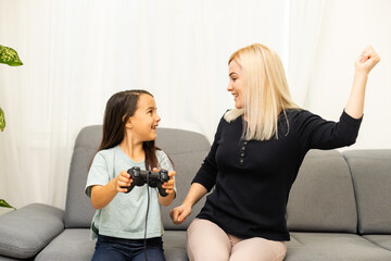 happy family together. mother and her child girl playing video games. family relax.