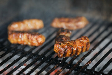 Shallow depth of field (selective focus) image with Romanian traditional mici (mititei), grilled ground meat rolls in cylindrical shape on the barbecue grill.