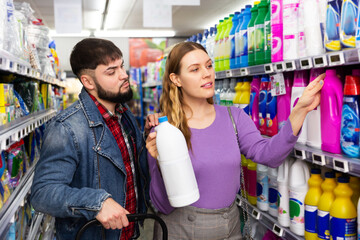 Young couple shopping at supermarket selecting detergent products