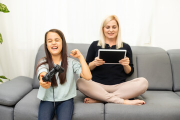 happy family together. mother and her child girl playing video games. family relax.