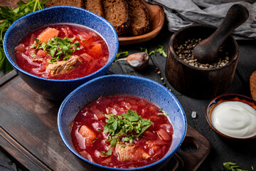  Two plates of borscht with sour cream on the table close-up - a dish of traditional Russian and Ukrainian cuisine. Red soup.