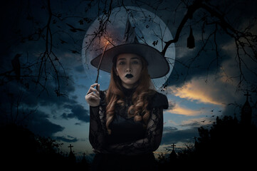 Halloween witch holding magic wand standing over cross, church, crow, bat, birds, dead tree, full...