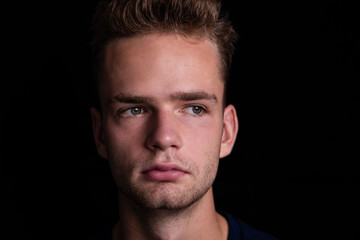 Obraz premium Portrait of handsome sad pensive unshaven guy on black background