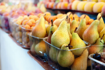 Ripe yellow pears and peaches lie on the market counter with other fruits. Farmer's harvest at the market