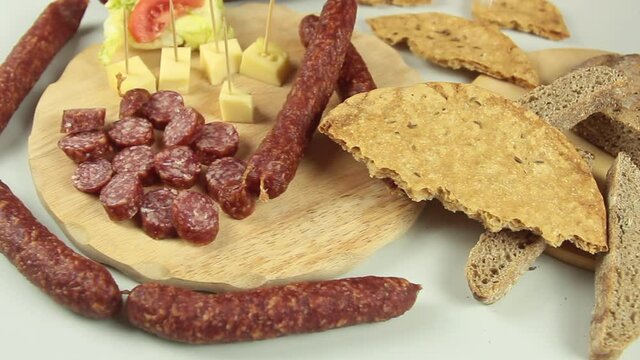 slider view of chefs hands serving a typical South Tyrolean snack plate like Tyrolean smoked sausage on a wooden cutting board accompanied by kaminwurz and paarl type bread