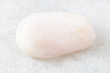 closeup of sample of natural mineral from geological collection - polished Petalite rock on white marble background