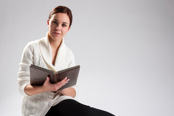Fototapeta premium Portrait of Young Caucasian Female Sitting and Reading Book.