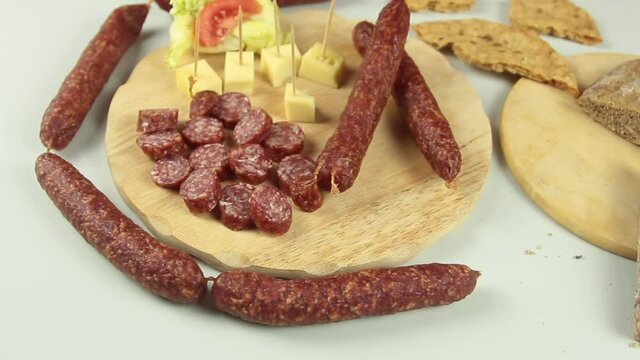 slider view of chefs hands serving a typical South Tyrolean snack plate like Tyrolean smoked sausage on a wooden cutting board accompanied by kaminwurz and paarl type bread