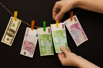 Close-up of a hand attaching removing 100 euros hanging from a clothespin on a rope with other...