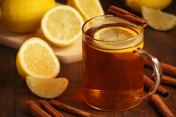 A mug with hot tea with lemons and cinnamon sticks