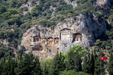 Fototapeta na wymiar Famous tombs carved inside rocks in ancient Kaunos city, Turkey. Lycian Royal mountain tombs carved into the rocks near the town of Dalyan in the province of Marmaris in Turkey