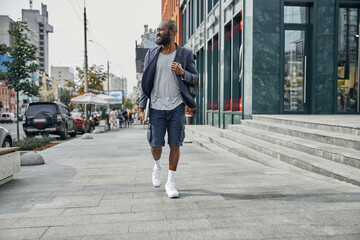 Cheerful dark-skinned man walking through the street