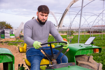 Confident farmer working on tractor in greenhouse. High quality photo