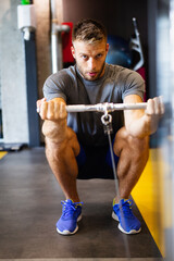 Fototapeta premium Young handsome man doing exercises in gym