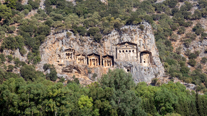 Fototapeta na wymiar Famous tombs carved inside rocks in ancient Kaunos city, Turkey. Lycian Royal mountain tombs carved into the rocks near the town of Dalyan in the province of Marmaris in Turkey