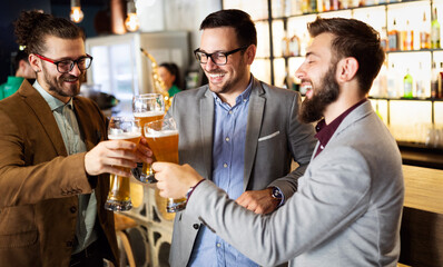 Business people drink beer after work in pub. Businessmen enjoy a beer.