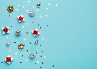 Christmas gold and silver decorations, mirror disco balls, gifts on pastel blue paper background.