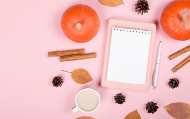 Autumn background with notepad, orange pumpkin, cinnamon and leaves on pink background