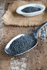 Poppy seeds in a spoon on rustic background