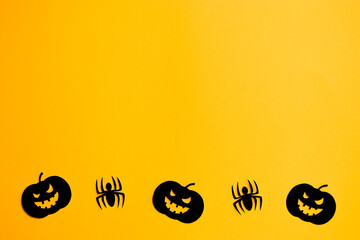 Black funny pumpkins and spiders on orange background. Halloween or dark evil power concept. Border with copy space for your design.