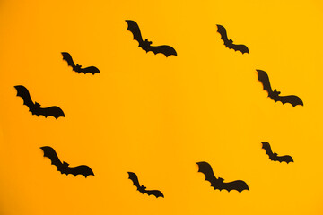 Frame of paper silhouettes of bats on orange background. Treat or trick Halloween holiday banner template with copy space in the middle.