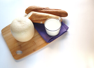 Round head of cheese with bread and milk on a