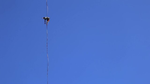 A man walks along the highline against the blue sky, Highliner goes on a stretched sling, Tightrope walker, A man catches balance.