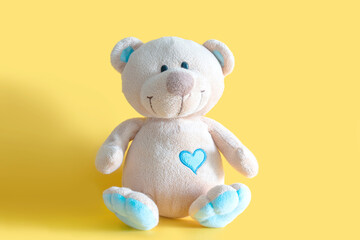 fluffy cute brown teddy bear toy sitting on yellow background with copy space