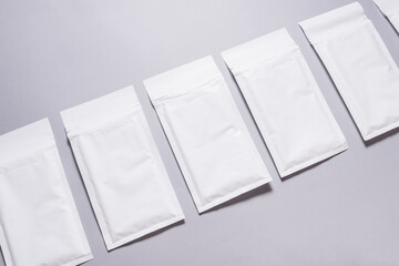 Lot of white paper bubble envelopes on grey background, textured background