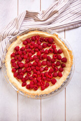 Preparation of shortbread pie with raspberries on white wooden background, top view