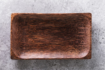 Empty dish made of wood on a table with concrete texture, top view. Food background