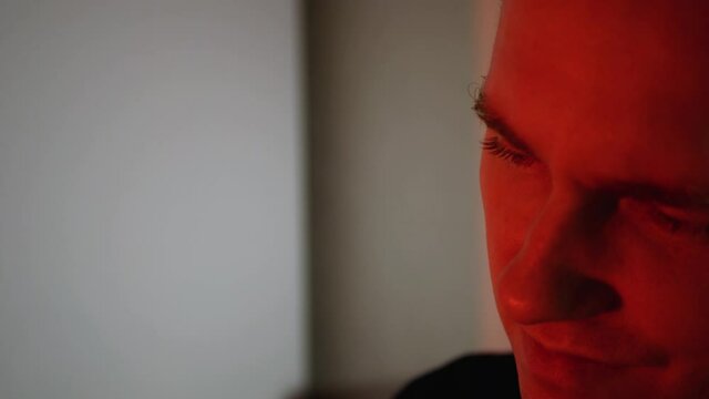 A young man with a serious look. Frowning man in red tones,evil smile emotion